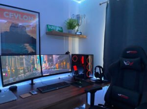 Gaming-Stuhl vor einem Schreibtisch mit Bildschirmen und beleuchteter Tastatur.
